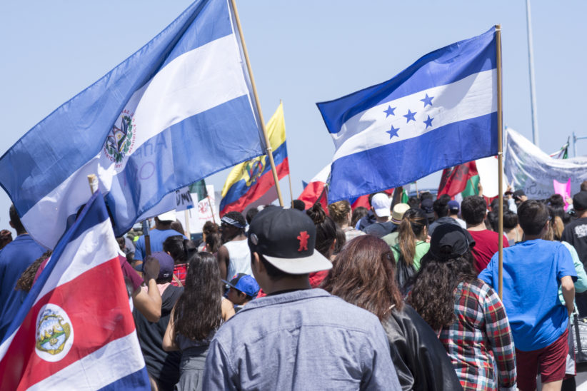 Protesters gather to march against Donald Trump outside a Trump rally in San Diego while carrying flags from Costa Rica, El Salvador, Honduras and other Central American nations.